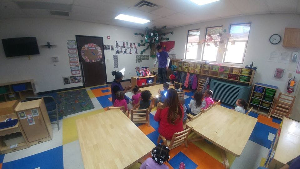 Adult and children sitting at tables in a classroom