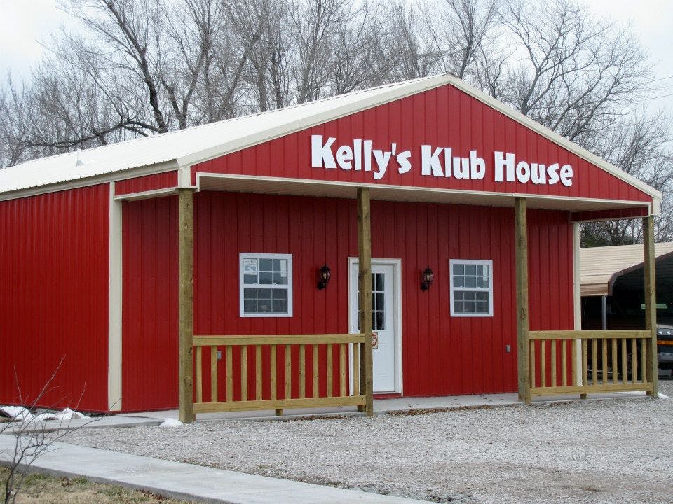 Red building with a white door and windows, sign reads "Kelly's Klub House"