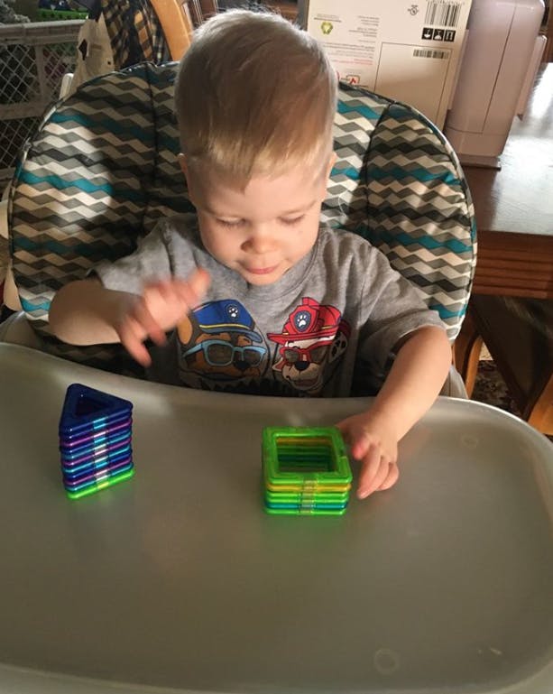 Child in a high chair playing with colorful magnetic blocks