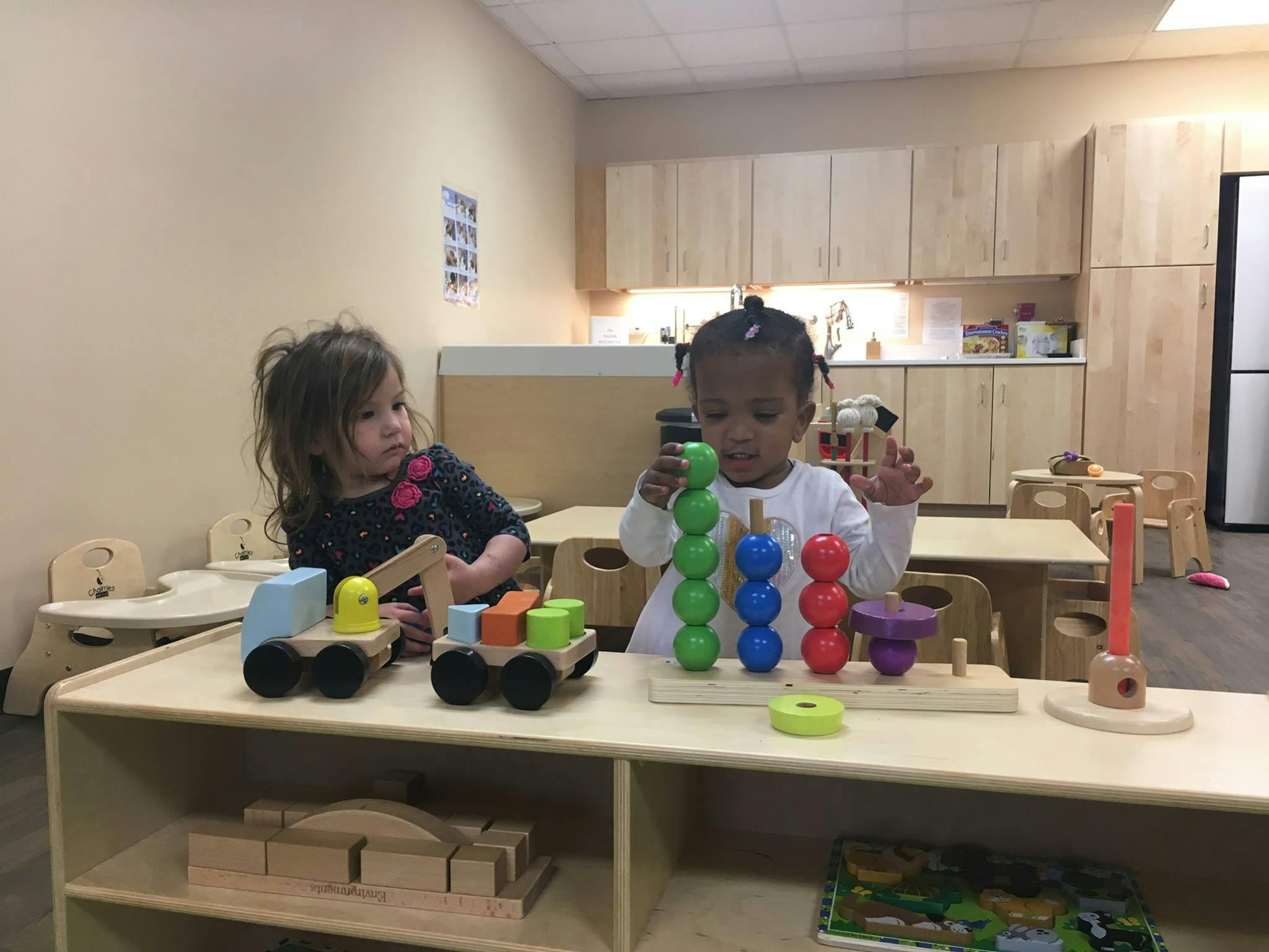 Two children playing with wooden toys in a classroom