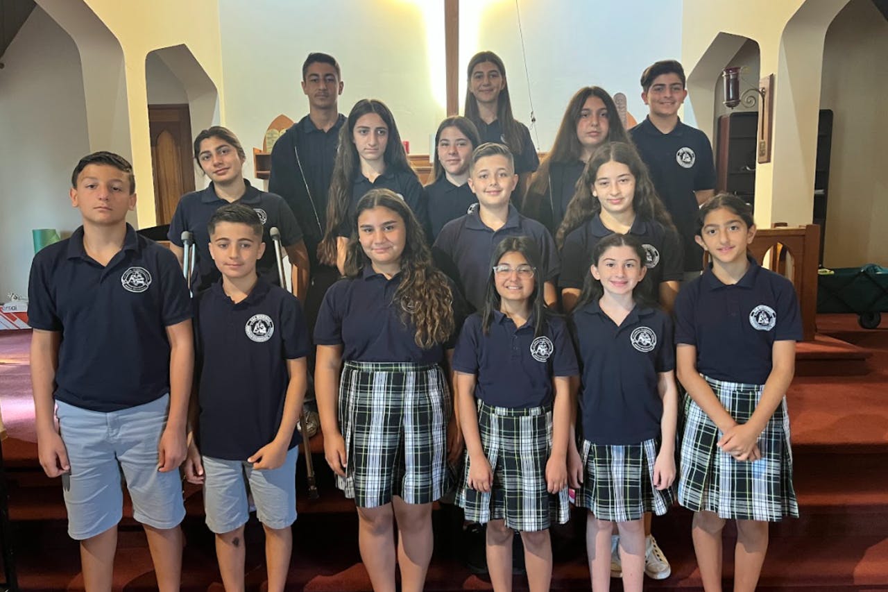 Group of children and teens in uniform polo shirts standing indoors