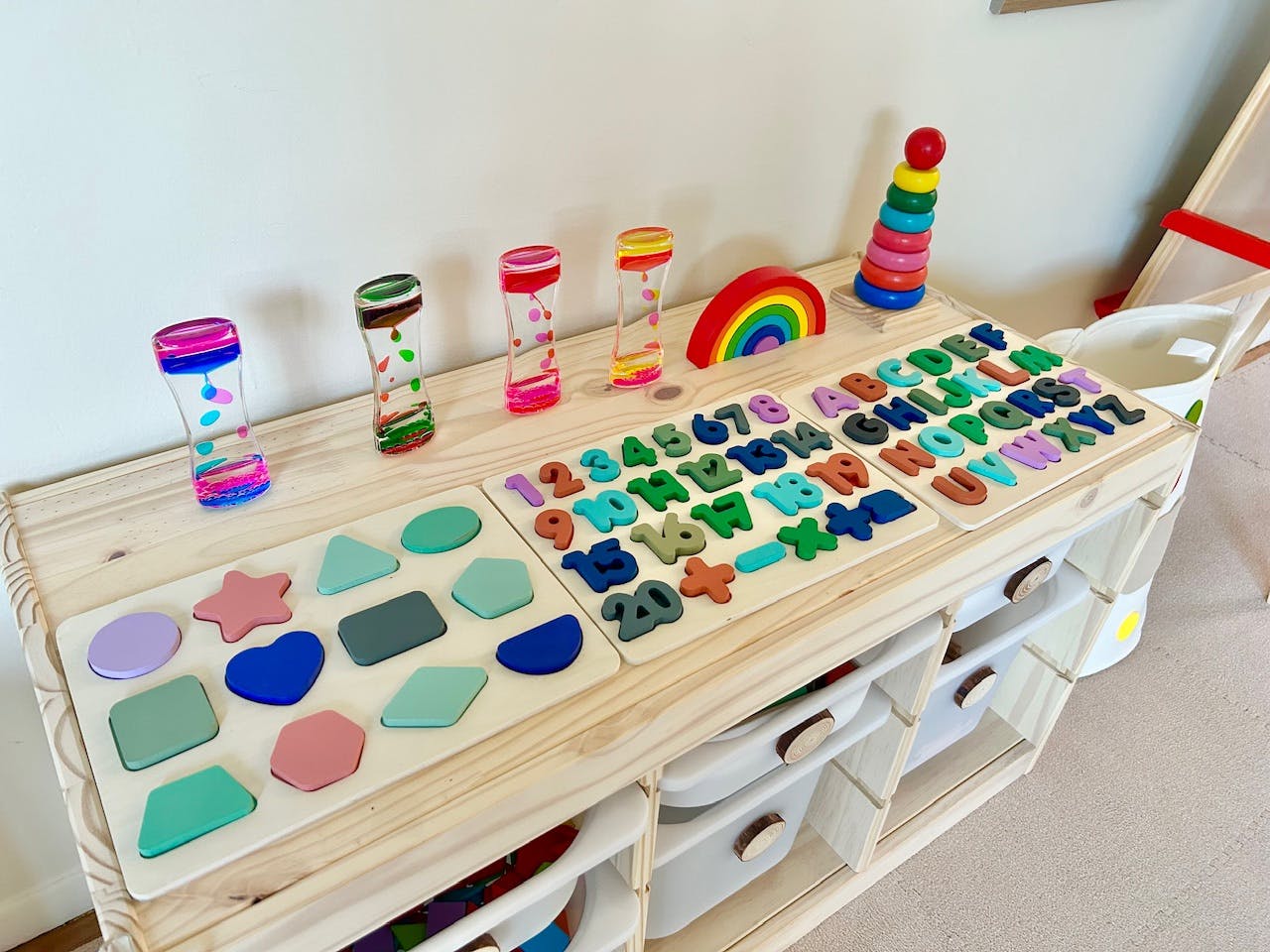 Wooden table with shape sorter, alphabet puzzle, and sensory bottles