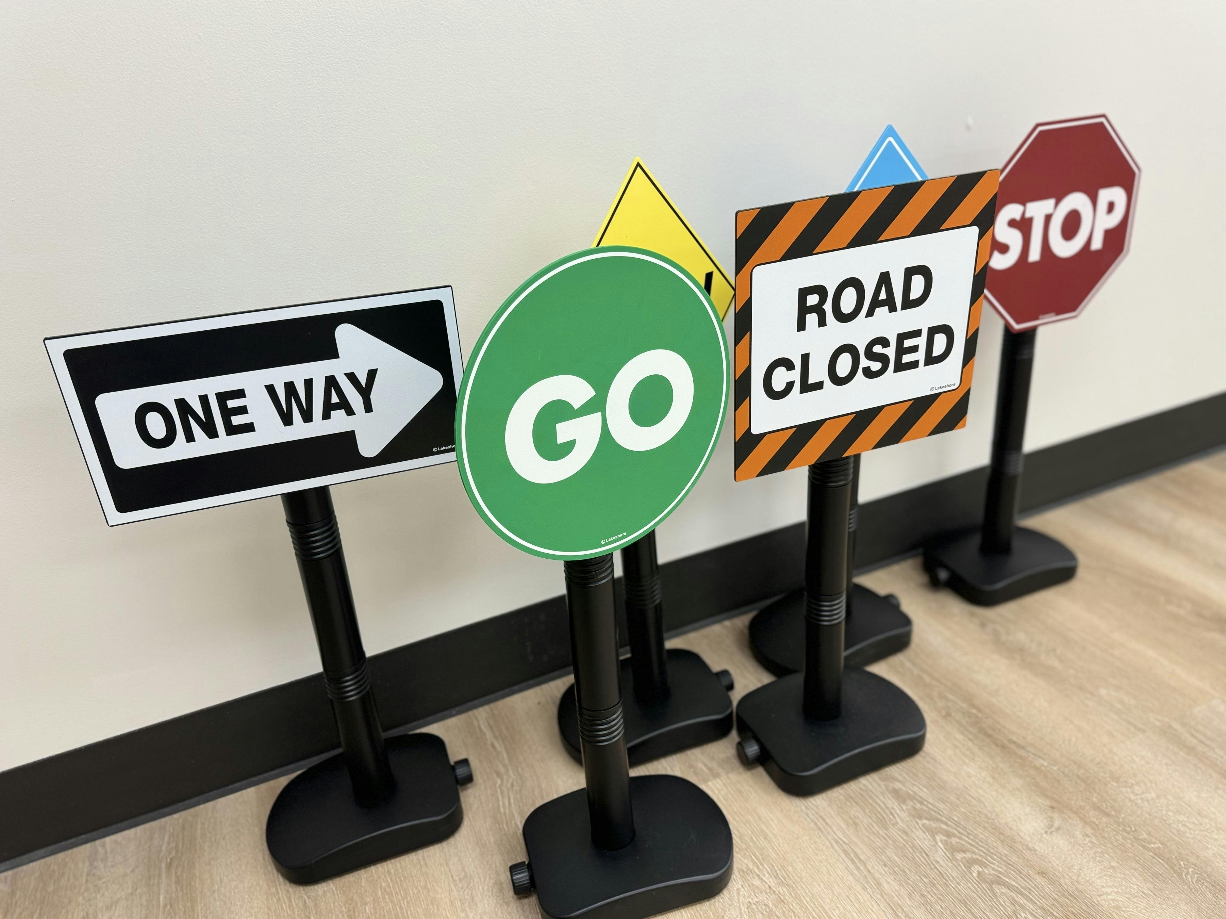 Five toy traffic signs, including one way, go, road closed, and stop