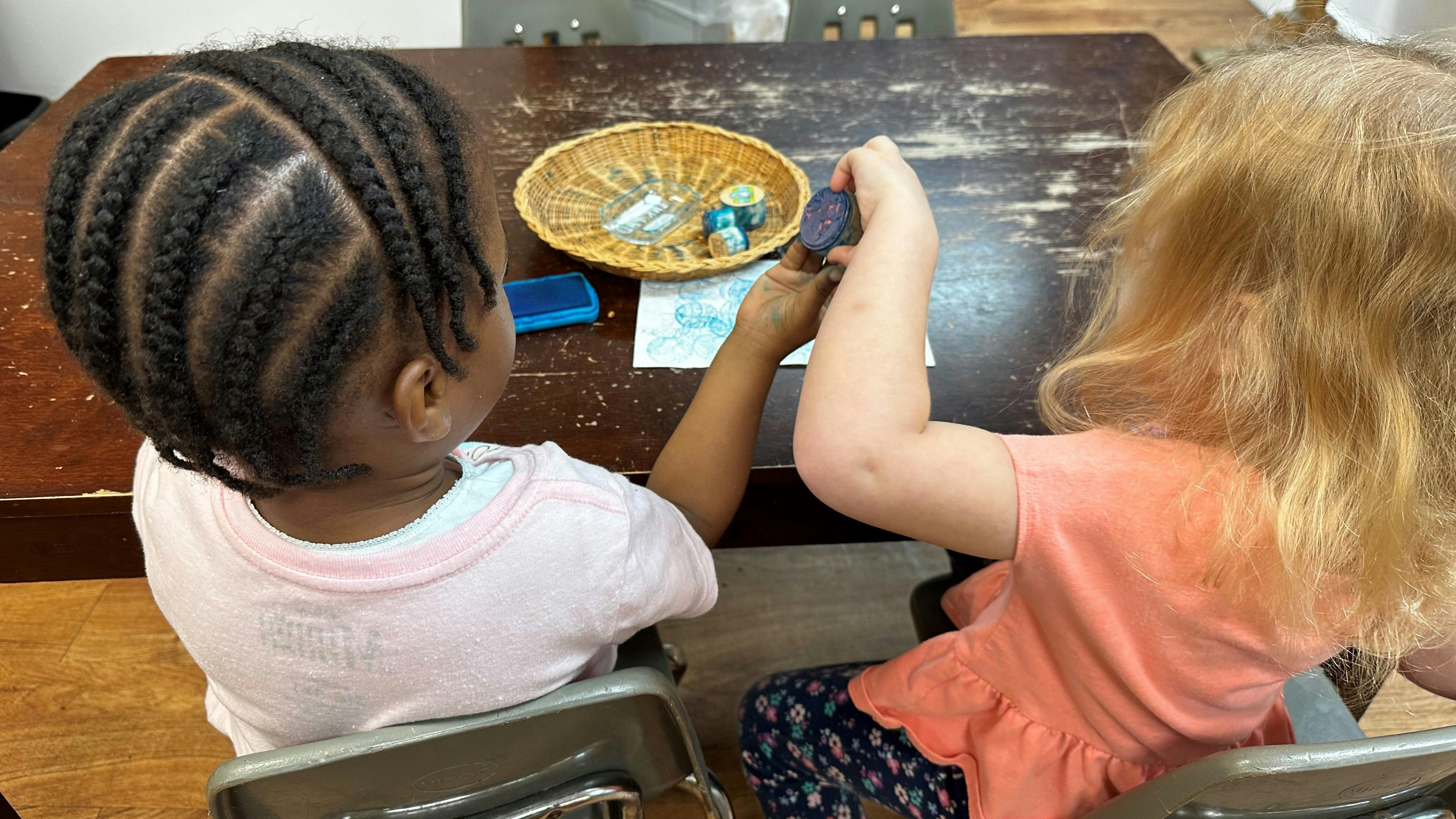 Two children sitting at a table playing with small objects