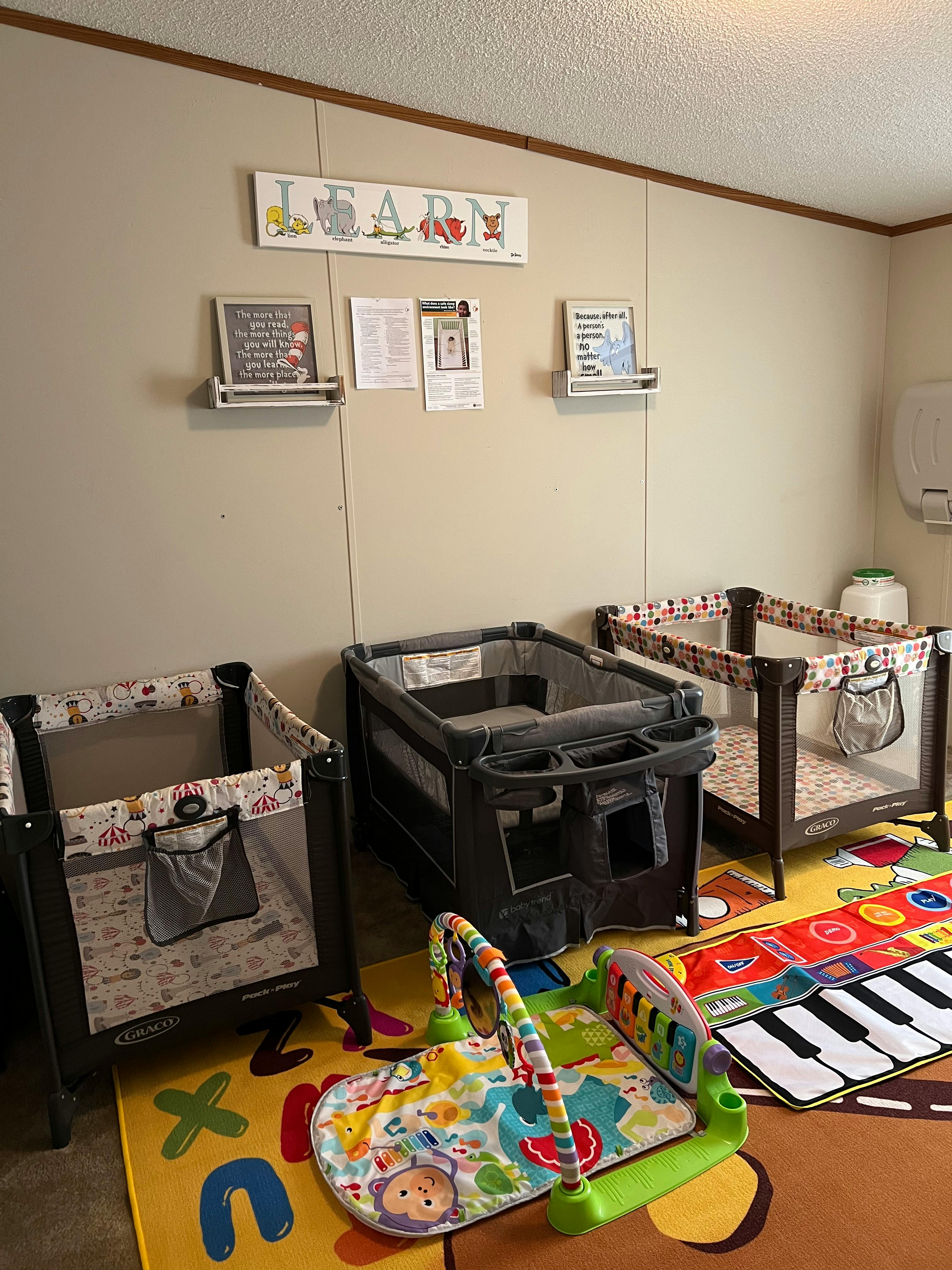 Three baby playpens and a play mat on a colorful rug
