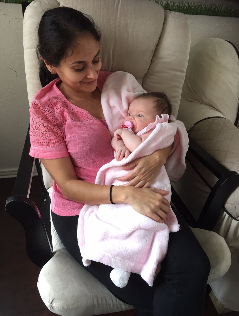 Person holding a swaddled infant with a pacifier