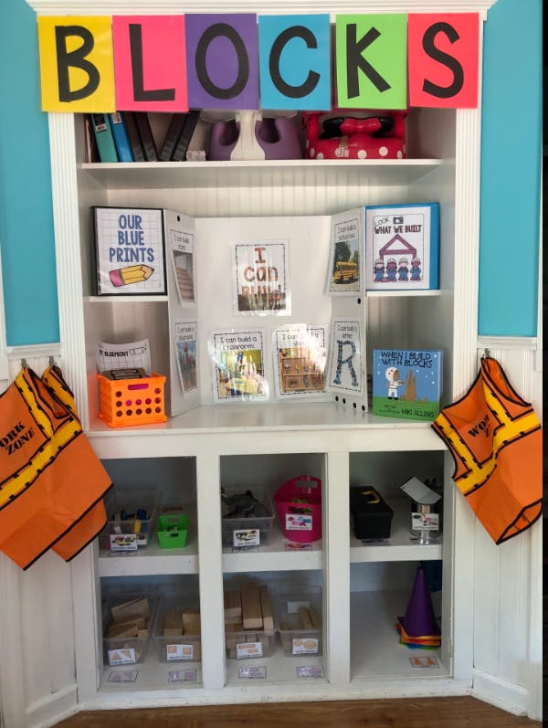 White shelving unit with "BLOCKS" sign, books, and building blocks