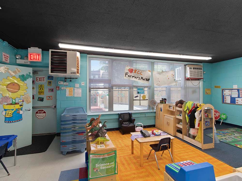 Classroom interior with toys, small tables, and art on walls