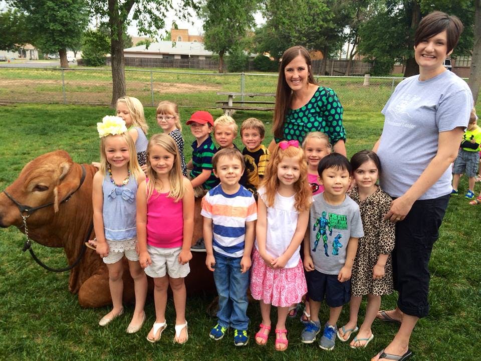 Two people and multiple children standing next to a cow