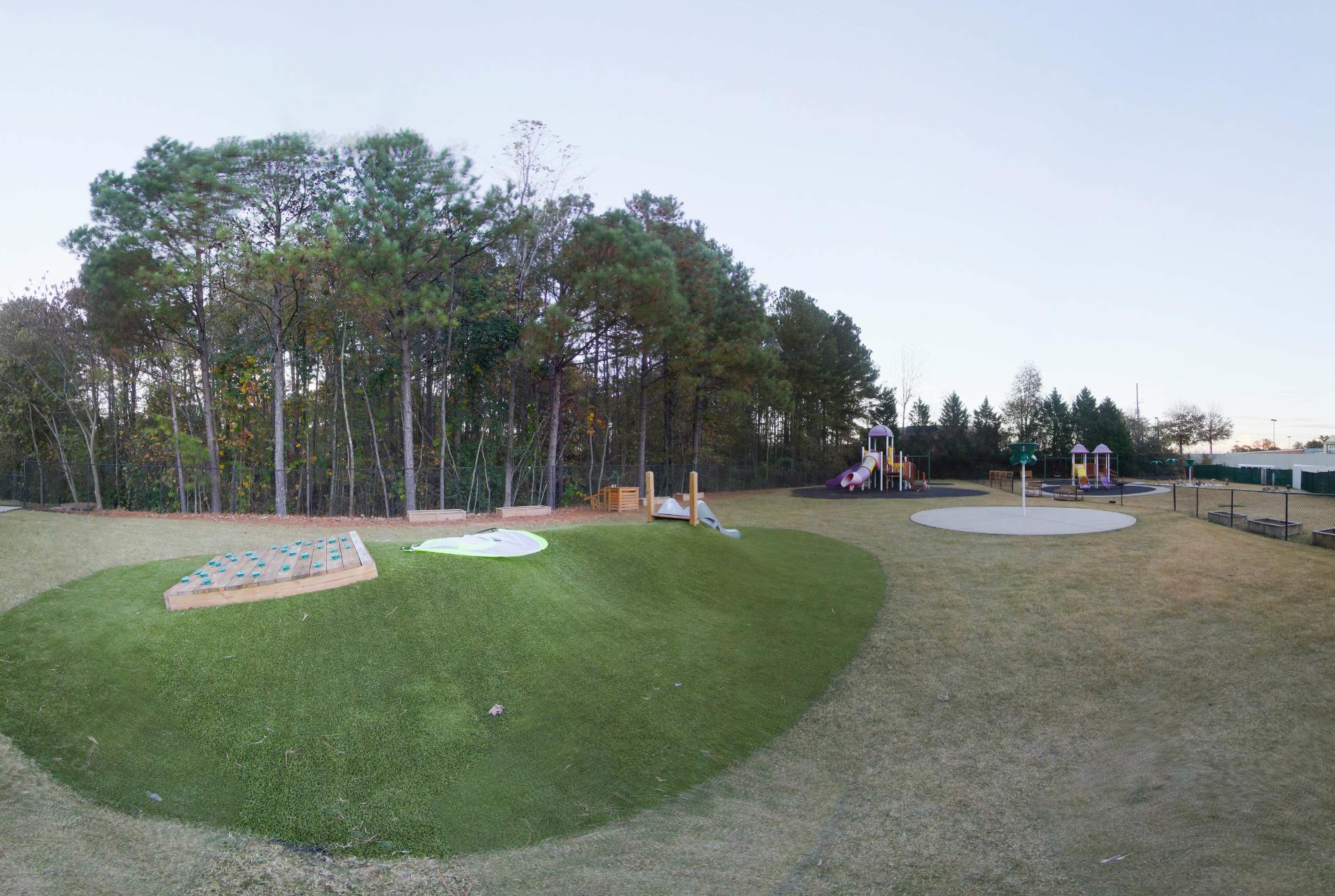 Outdoor playground with multiple play structures and artificial grass hills