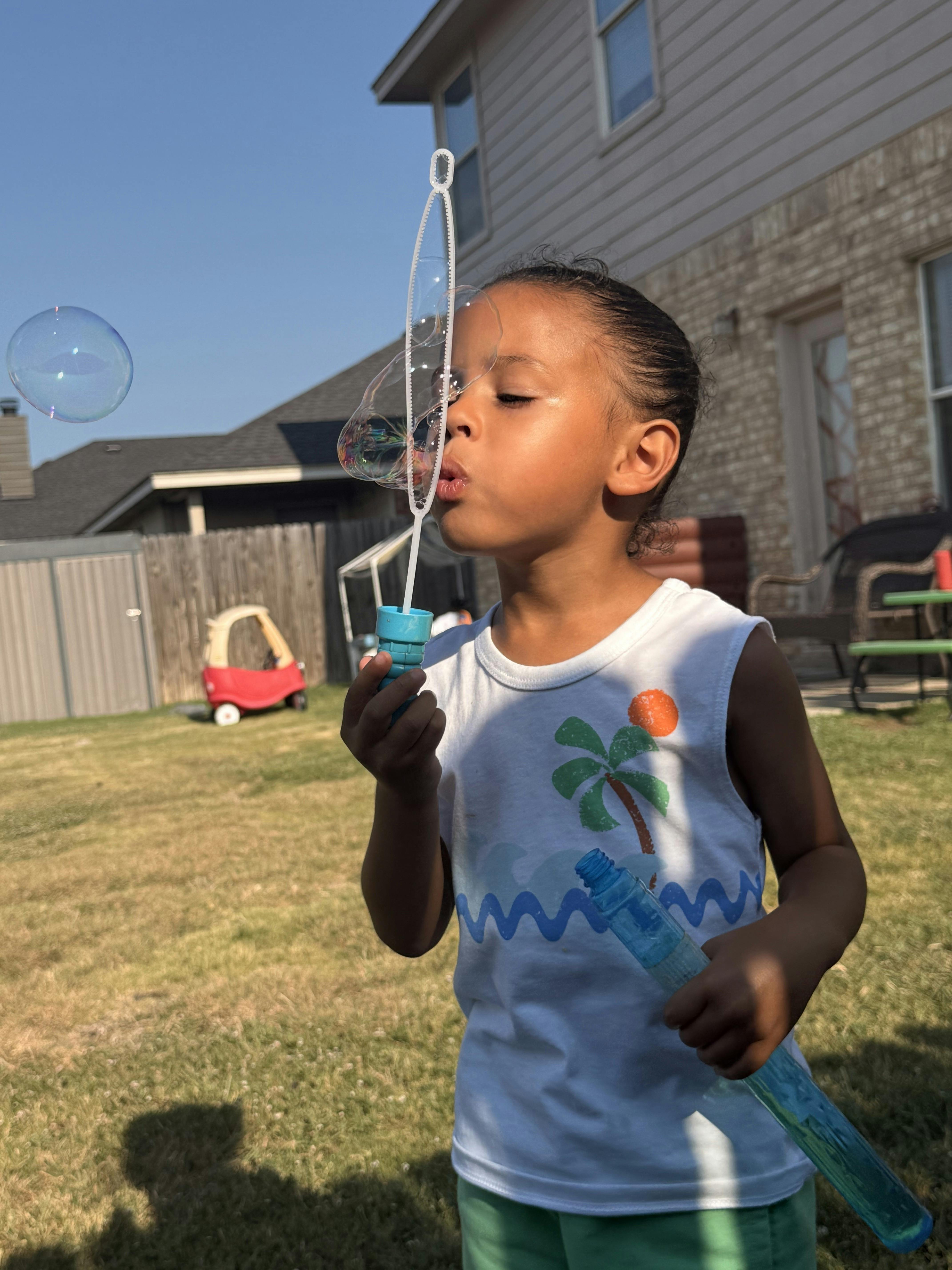 Child blowing bubbles in a backyard