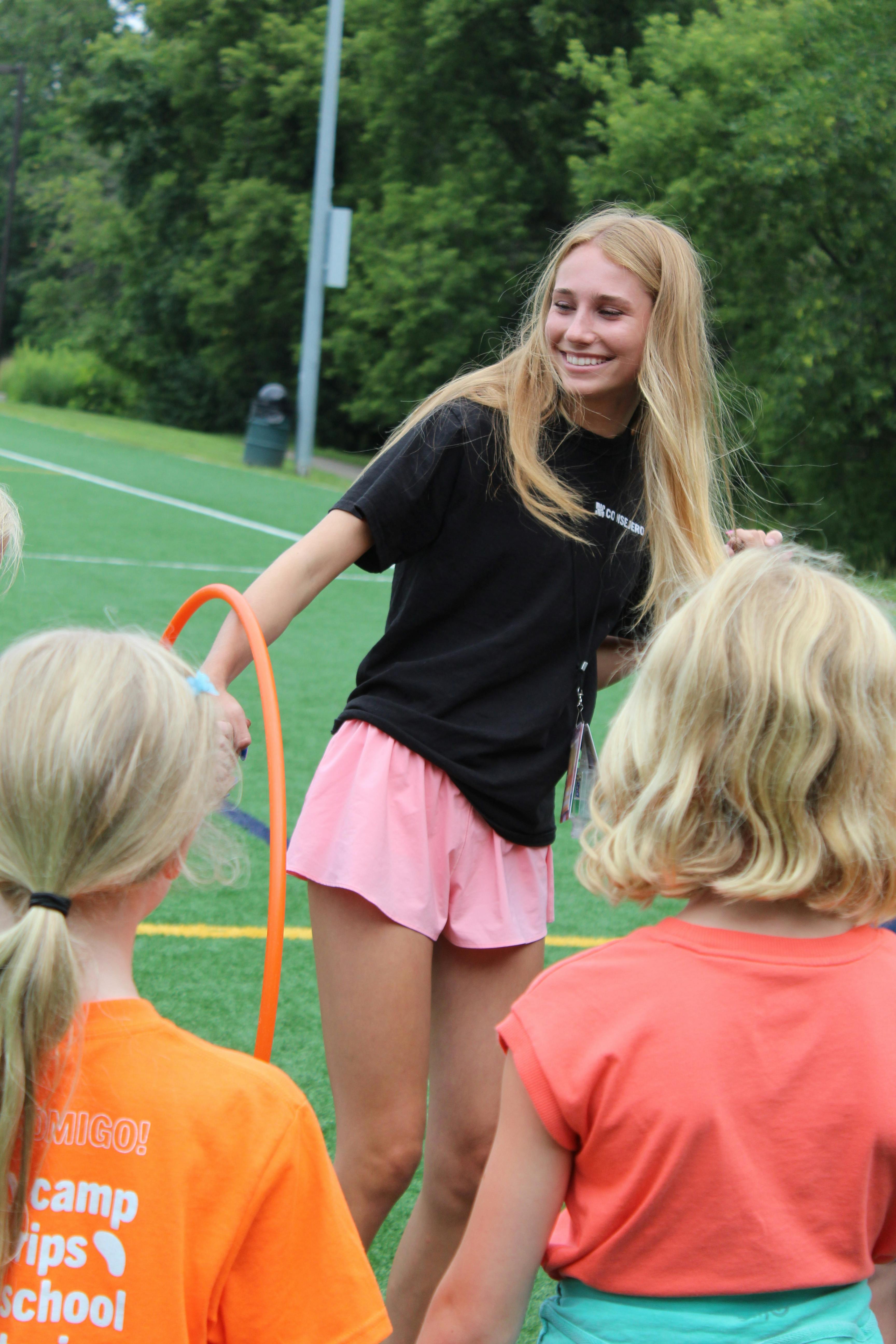 Person holding a hula hoop with two children on a field