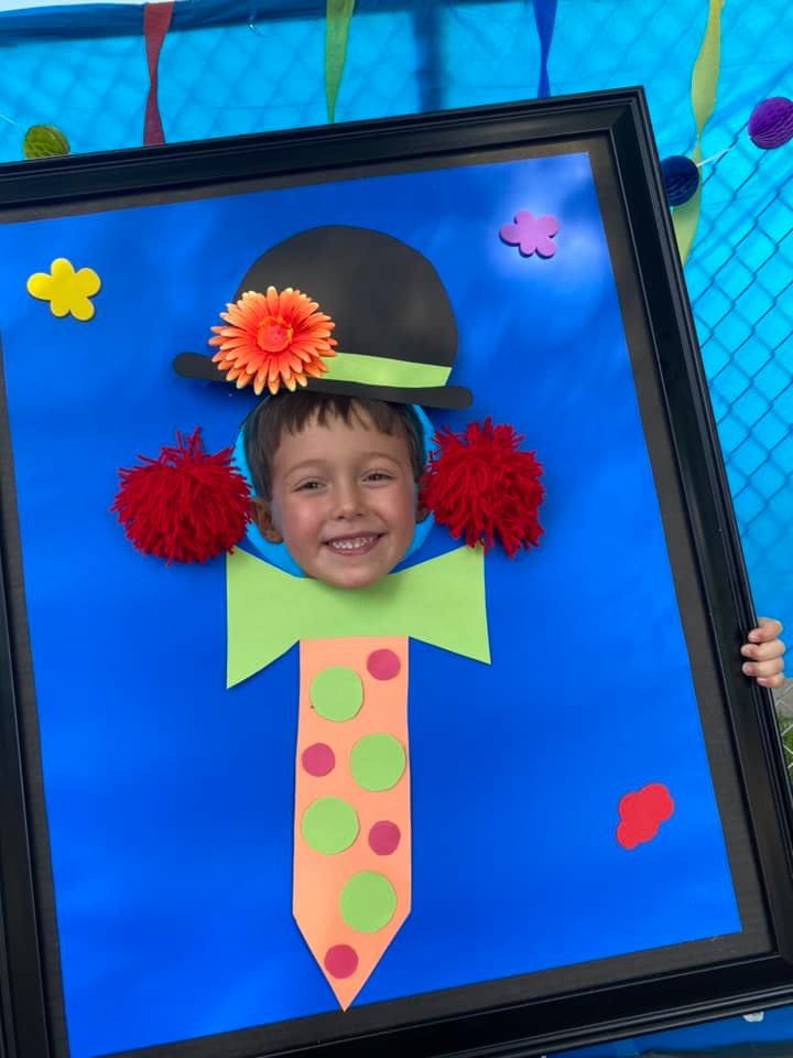 Child's face in a cutout of a clown costume
