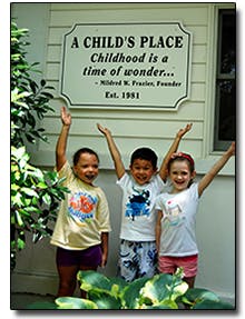 Three children with arms raised under a sign that reads "A Child's Place"
