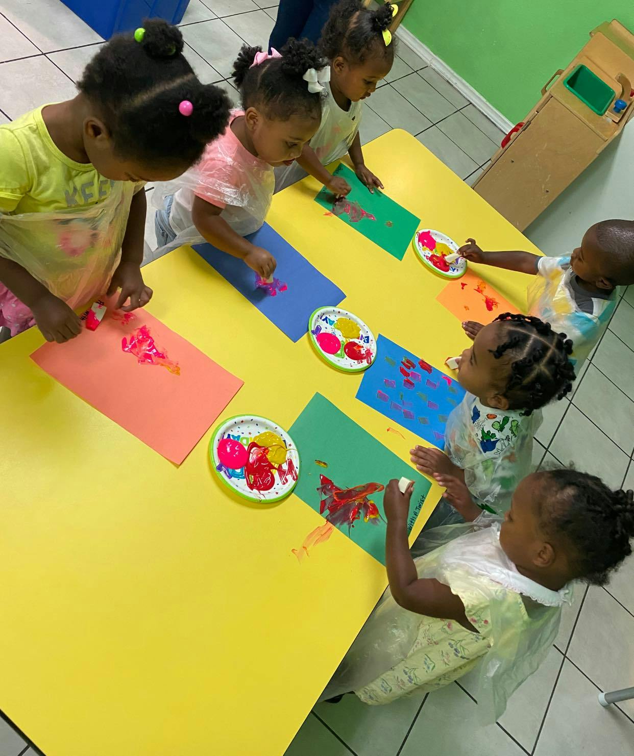 Children painting at a yellow table