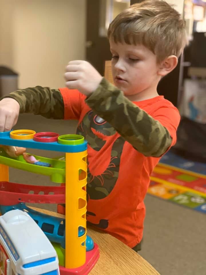 Child playing with a colorful toy ramp
