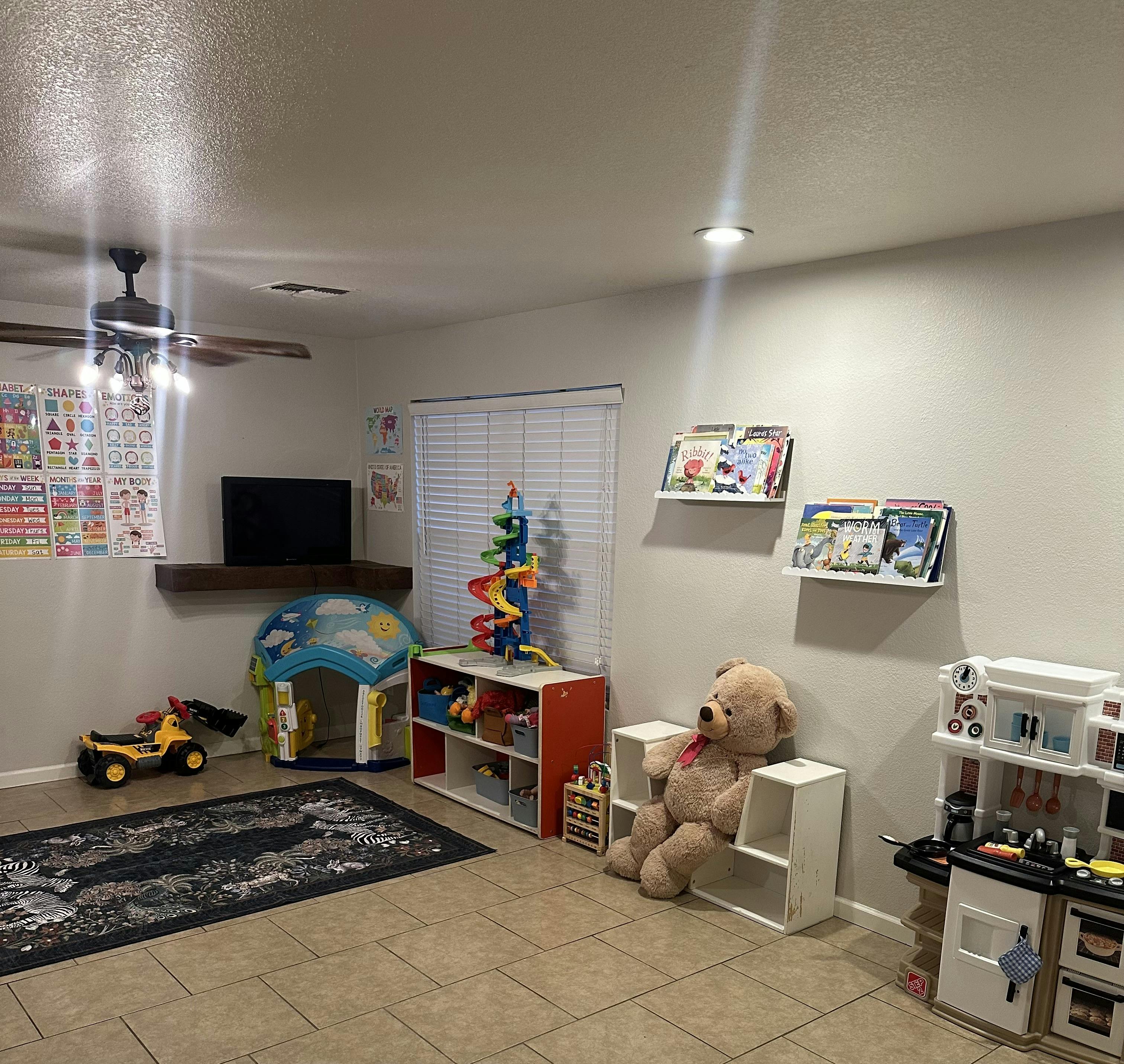 A playroom with various toys, books, and educational charts on the wall