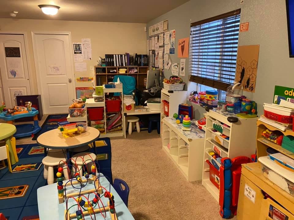 Playroom with small tables, chairs, and shelves filled with toys