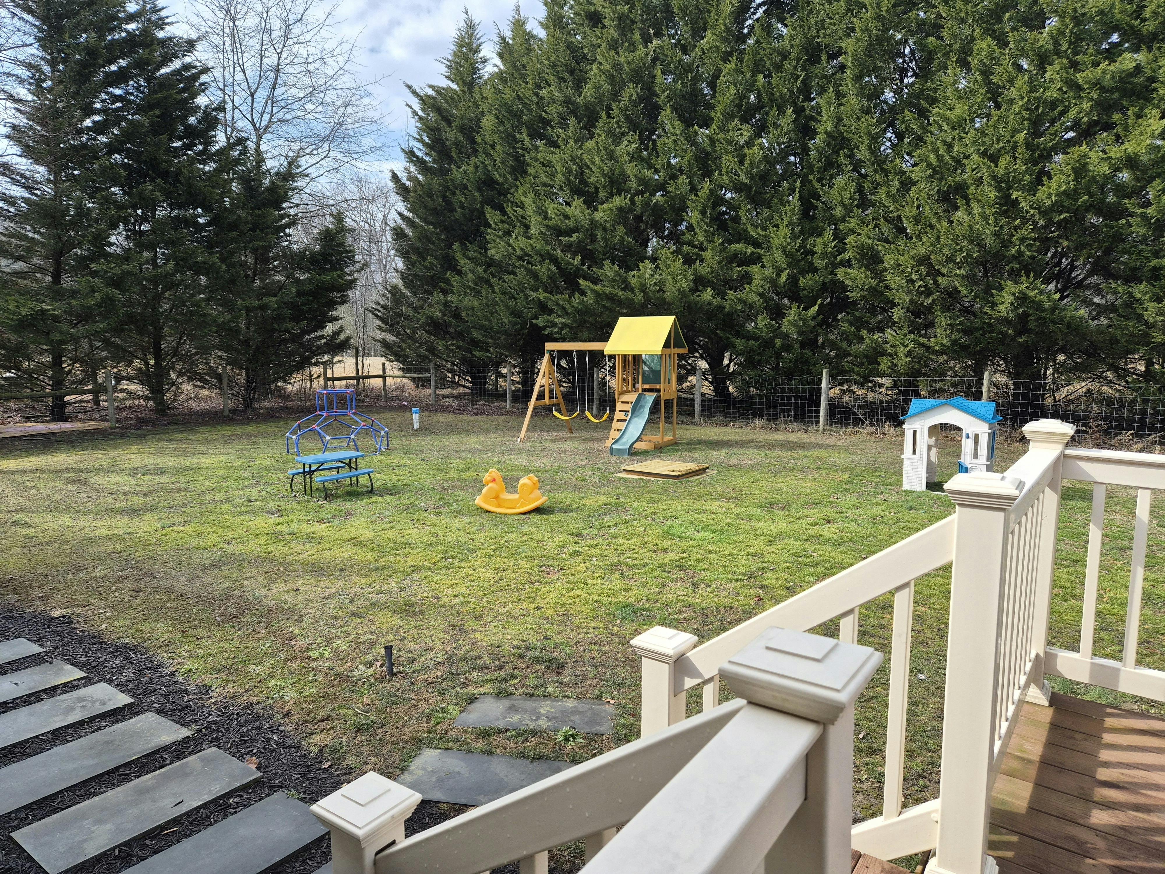 Backyard with a wooden swing set, slide, blue dome climber, and playhouse
