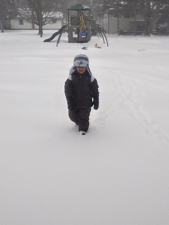 Child walking in snow with playground in background