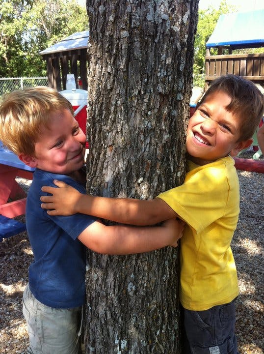 Two children hugging a tree