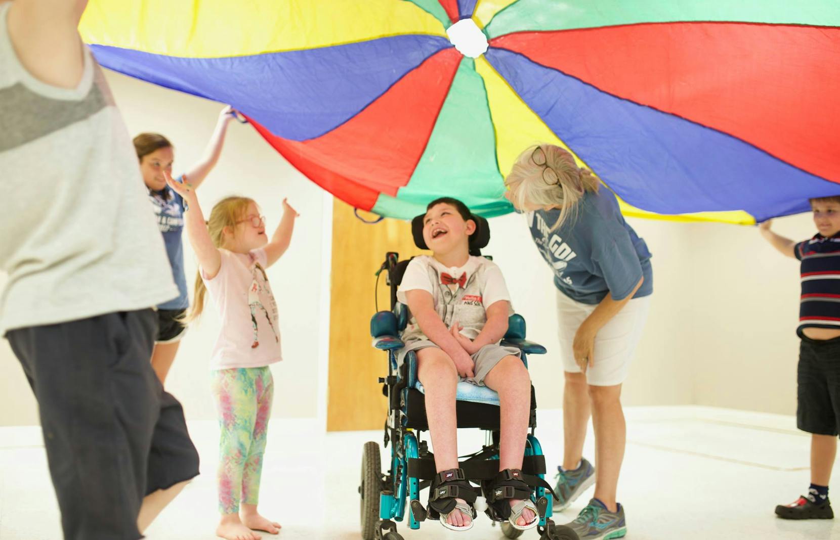 Children playing with a colorful parachute, one child in a wheelchair