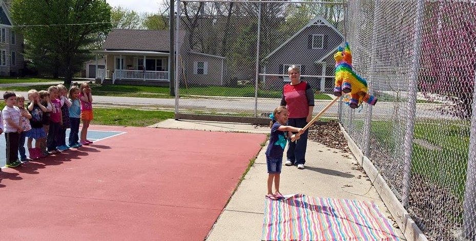 Child hitting a piñata with a stick while other children watch