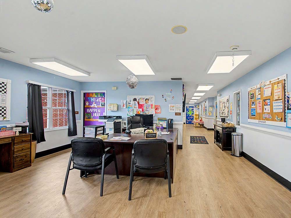 Classroom or daycare center with a large desk, chairs, and bulletin boards
