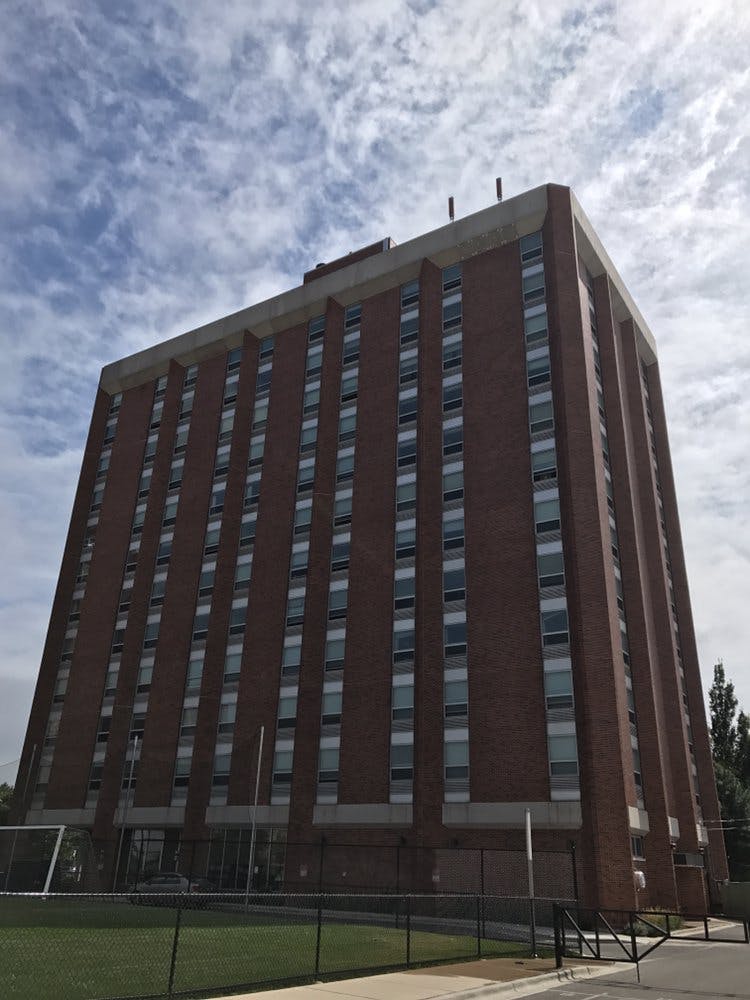 Tall brick building with many windows against a cloudy sky