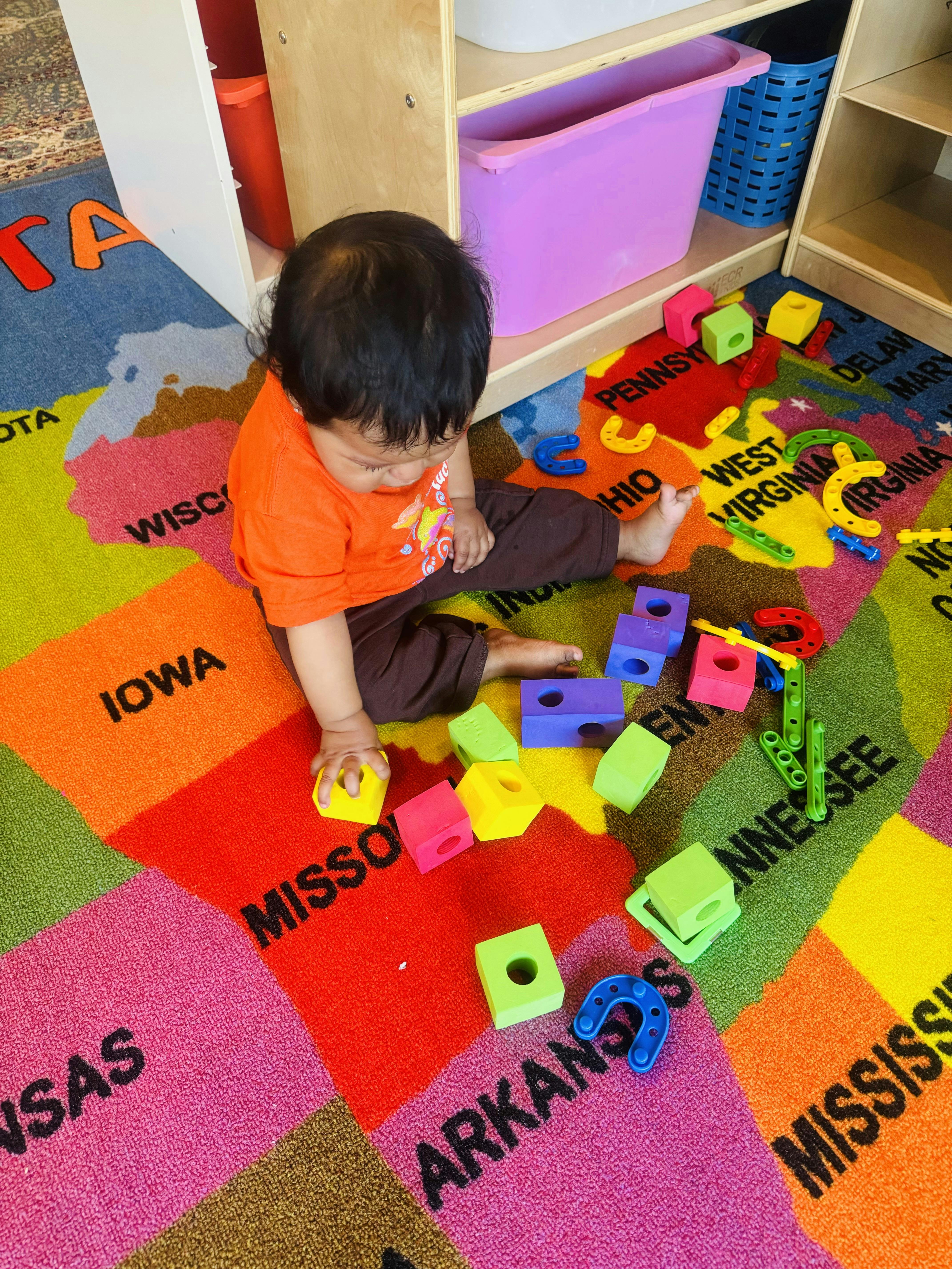 Child playing with colorful blocks on a map rug