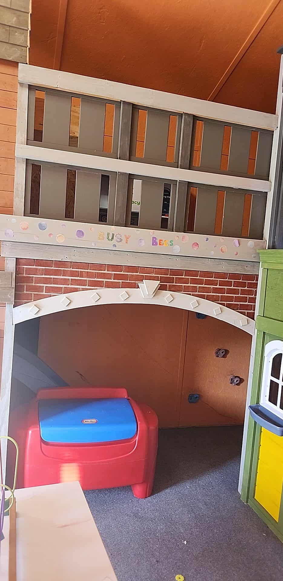 Play structure with a red and blue toy box under an archway