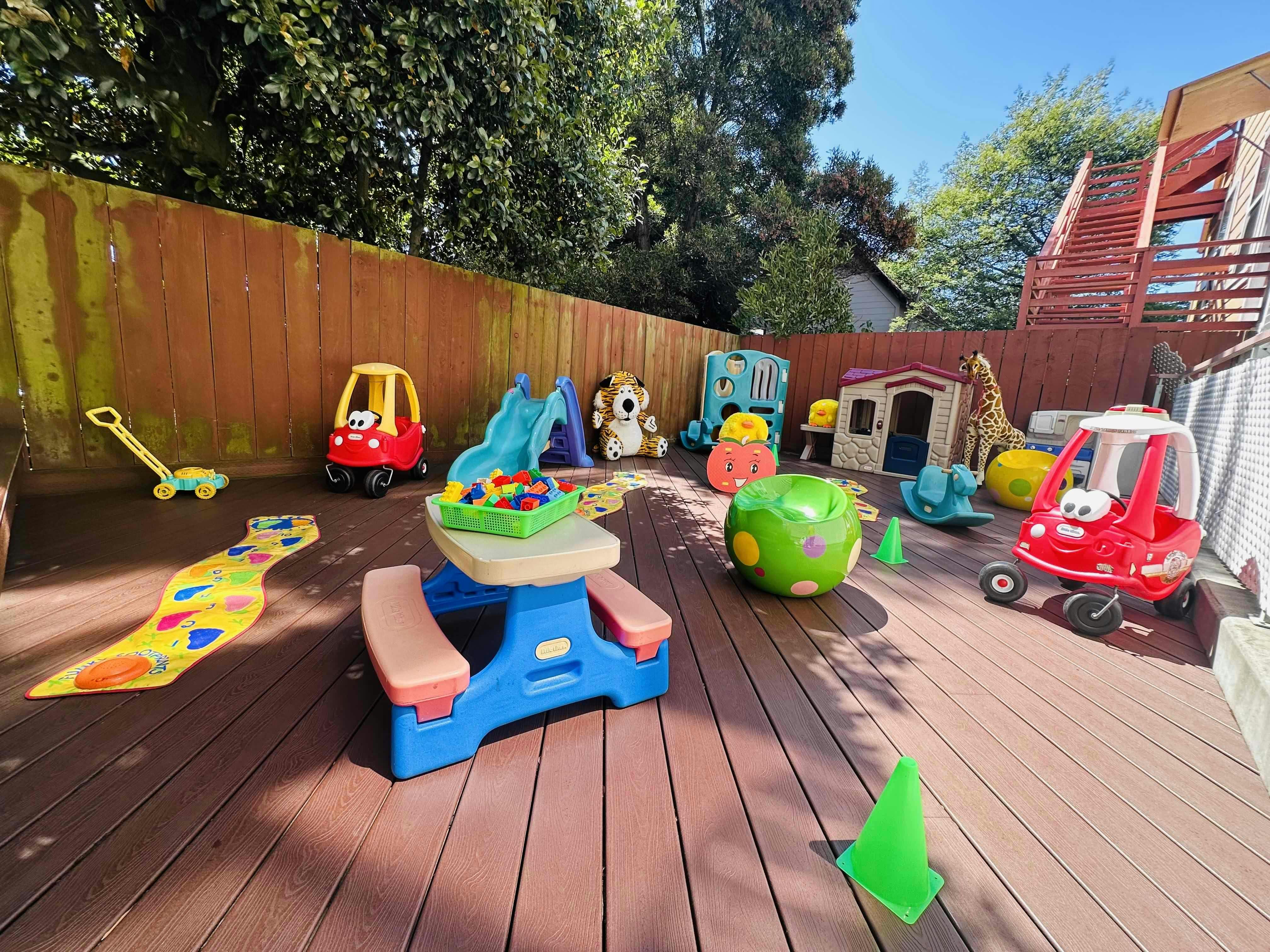 Plastic toys and a small picnic table on a wooden outdoor deck