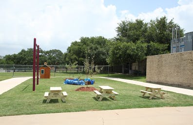 Outdoor area with picnic tables, a small playhouse, and a blue tarp