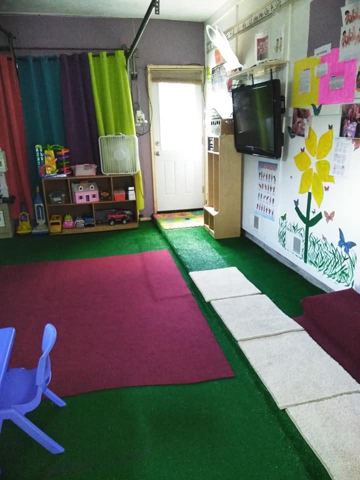 Indoor play area with green turf, red mat, and wall decorations