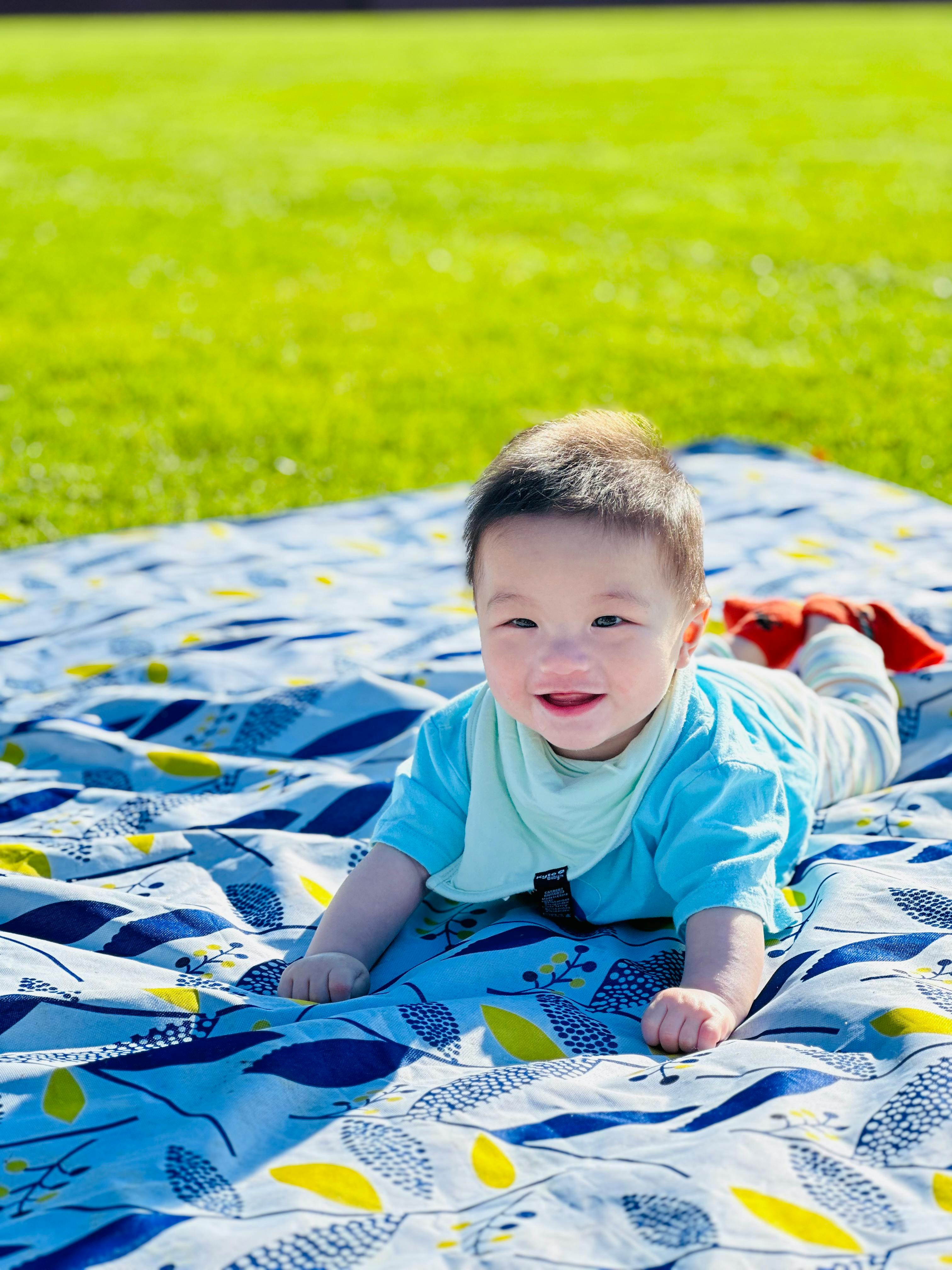 Child on a patterned blanket on grass