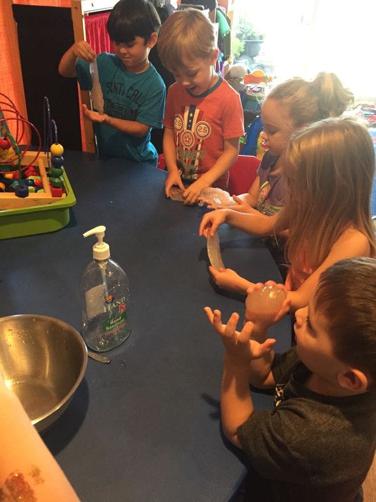 Children at a table holding clear plastic items