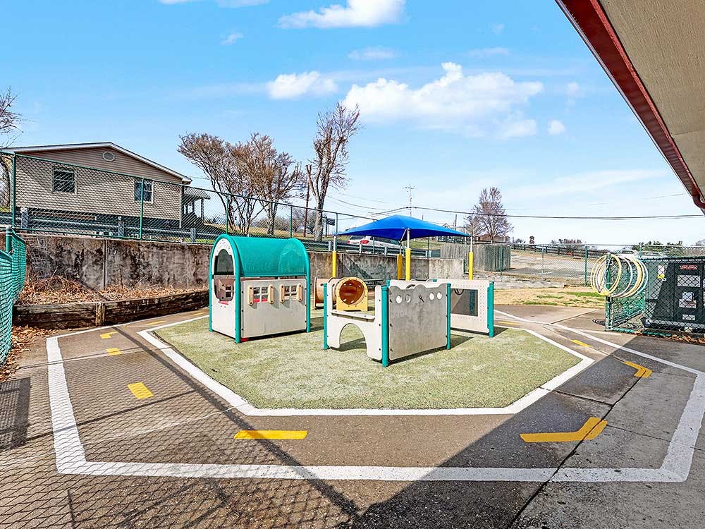Empty children's playground with small playhouses and a blue umbrella