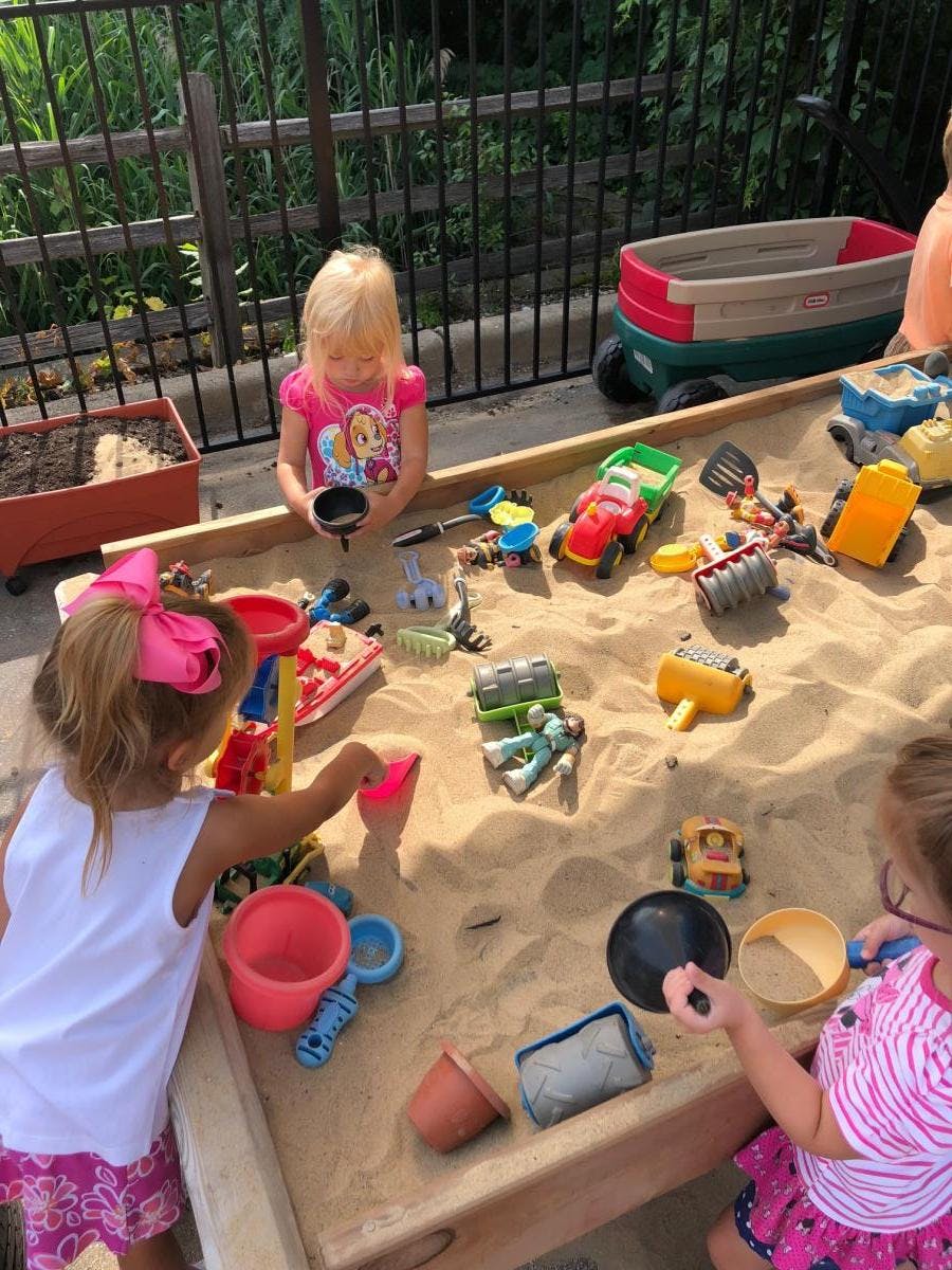 Children playing in a sandbox with toys