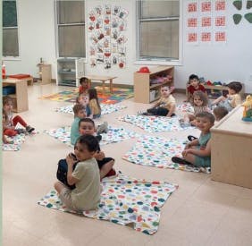 Children sitting on blankets in a classroom