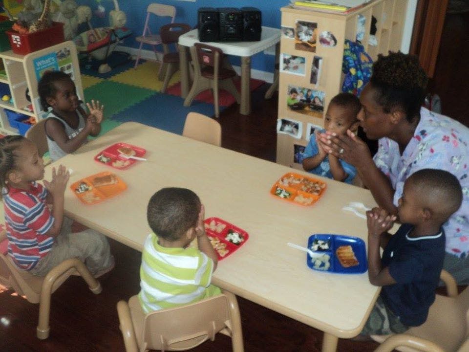 Adult and children eating at a table in a classroom