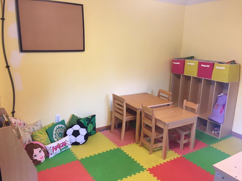Classroom with small tables and chairs, cubbies, and floor cushions