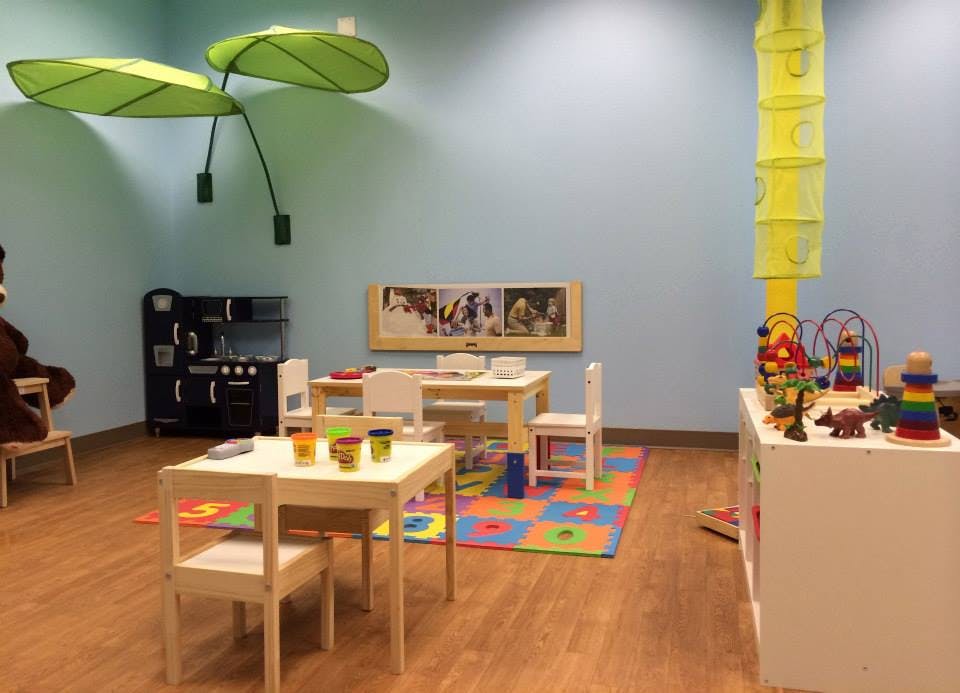 Playroom with small tables and chairs, play kitchen, and toys