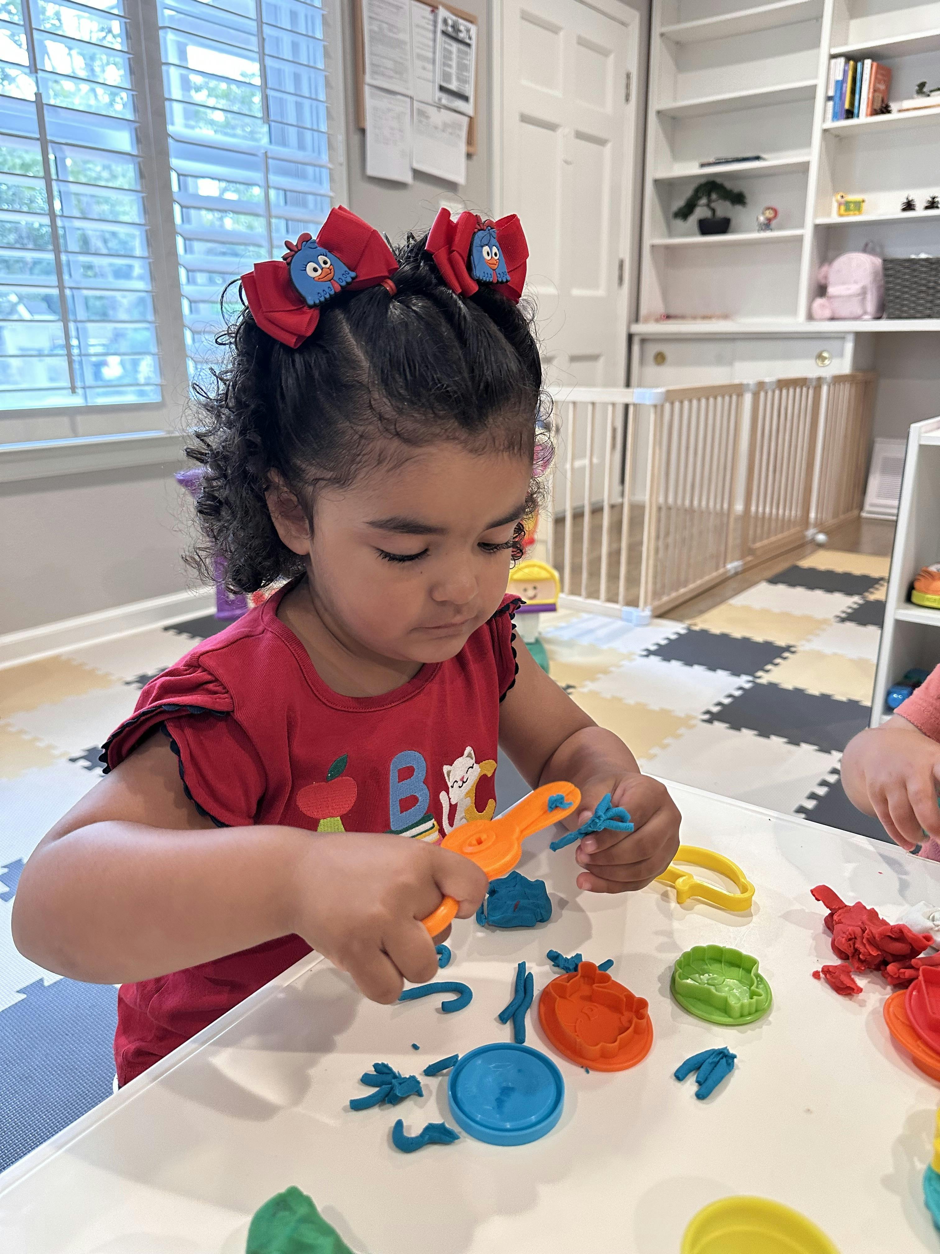 Child playing with colorful playdough and tools at a table