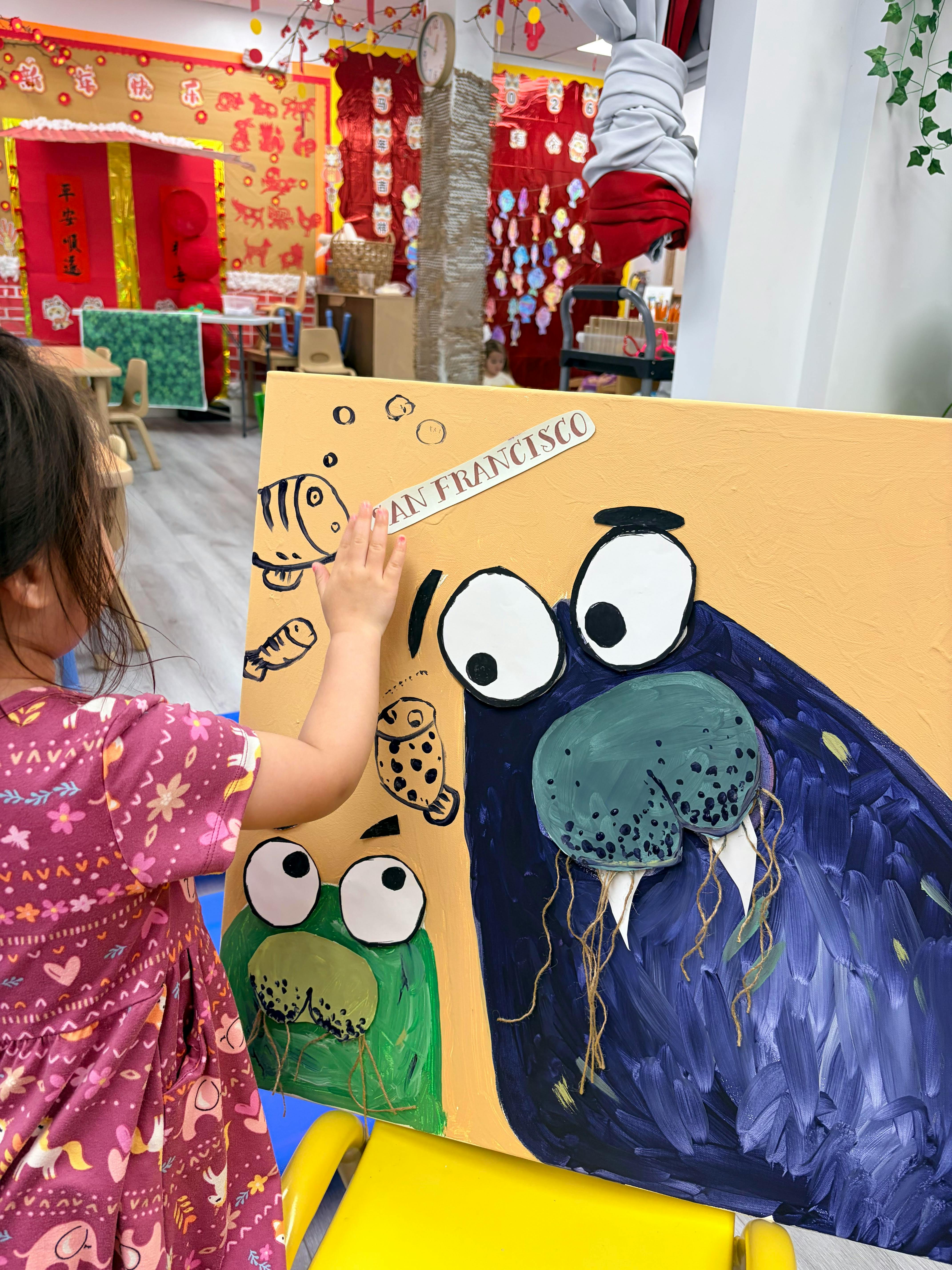 Child placing a "SAN FRANCISCO" sticker on a cartoon painting