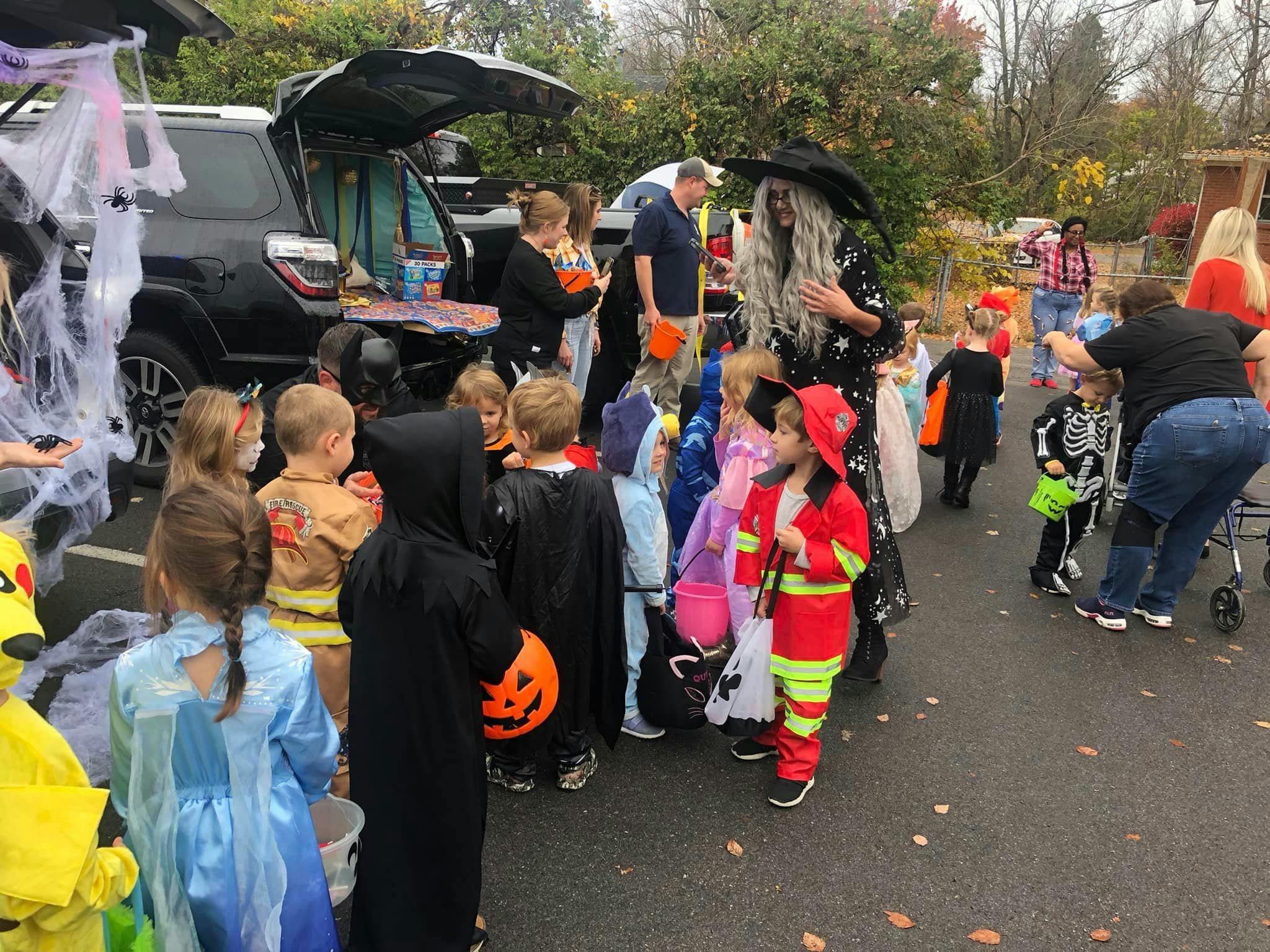 People and children in Halloween costumes gathered around a vehicle