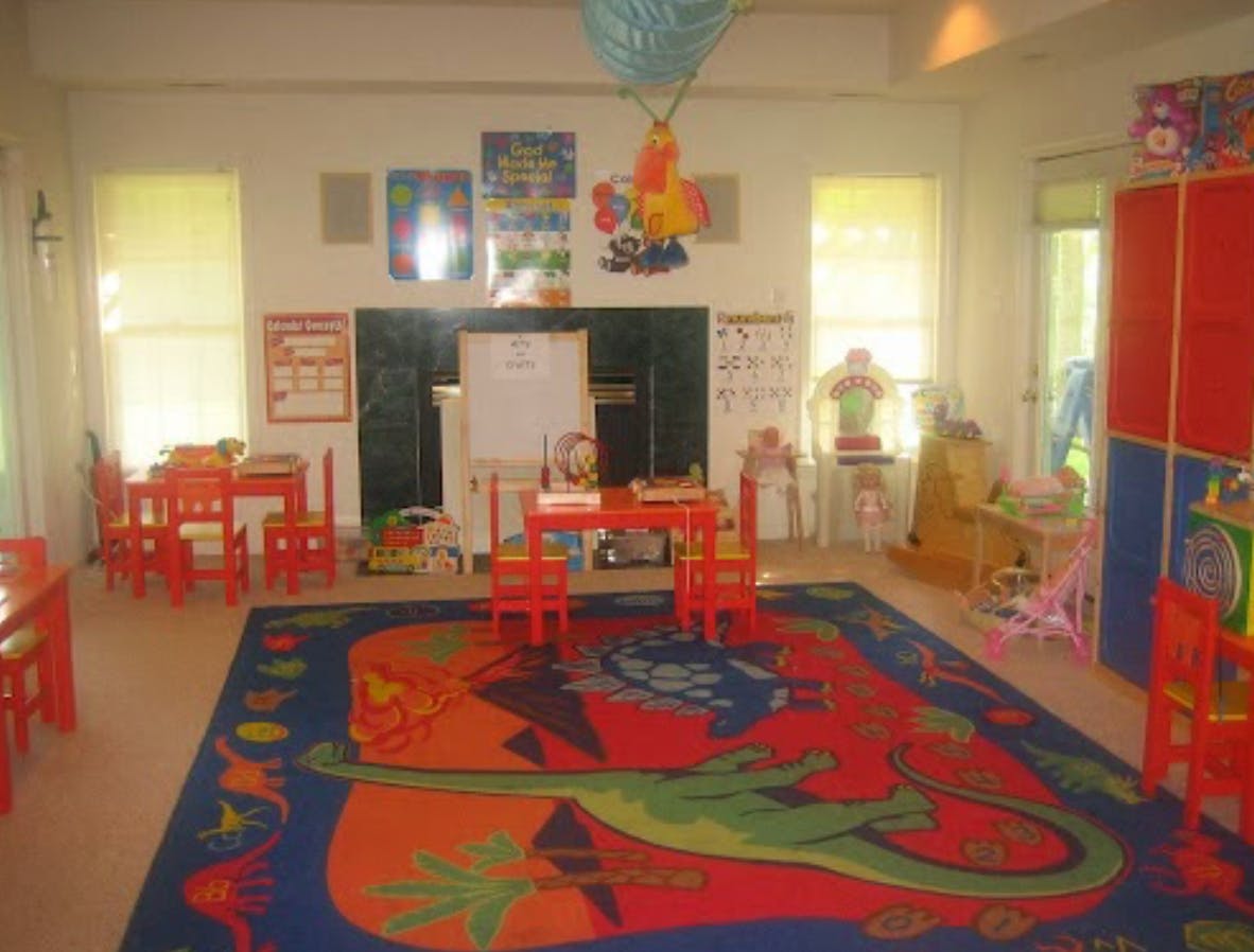 Classroom with small red tables and chairs, colorful rug