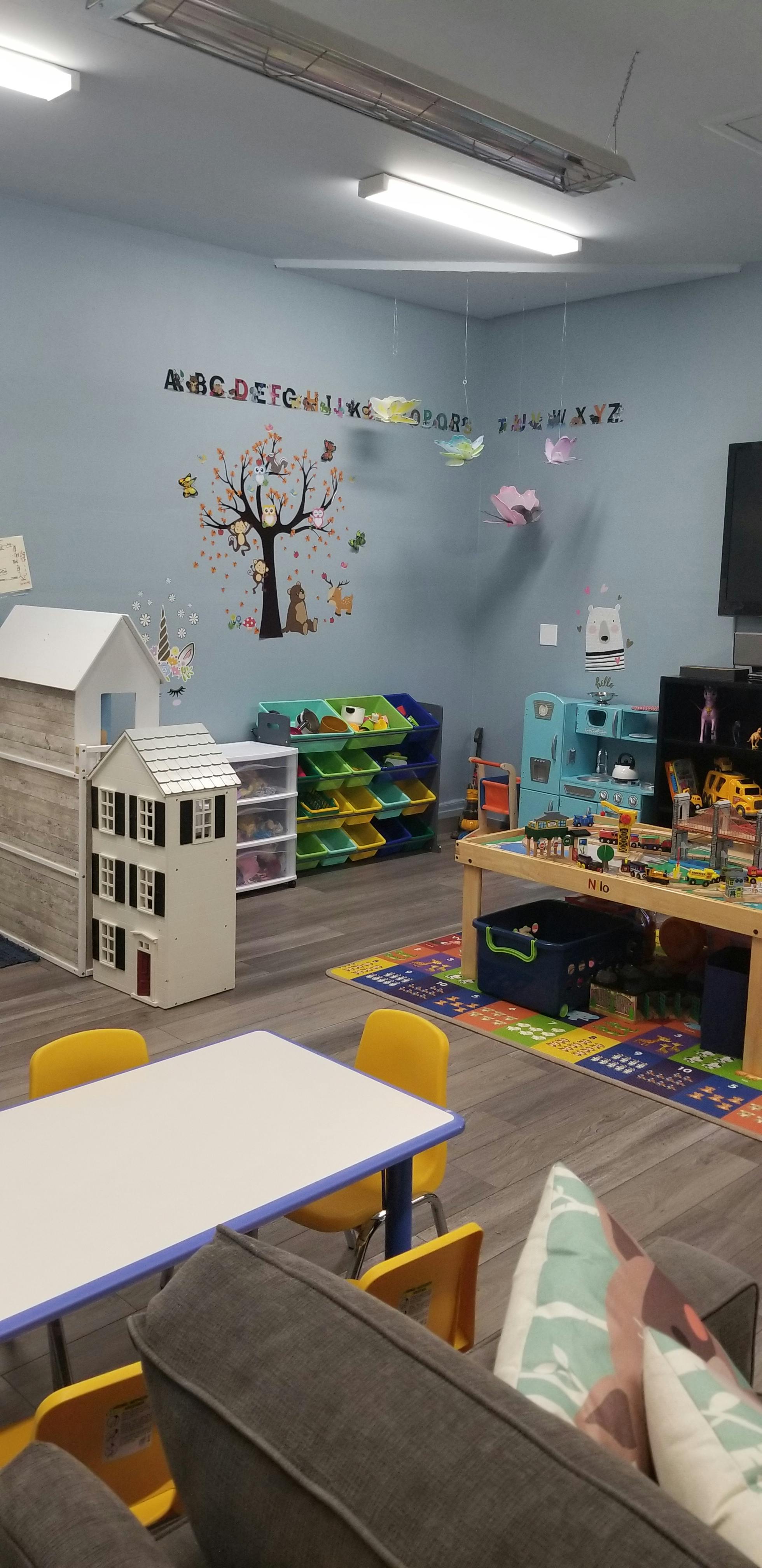 Children's play area with a table, chairs, dollhouse, and toy storage