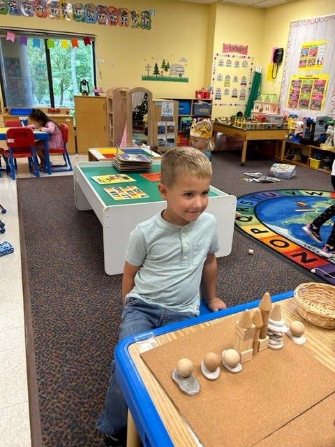 Child sitting at a table with building toys in a classroom