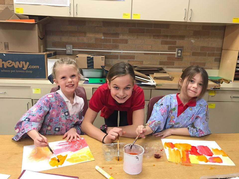 Three children painting at a table