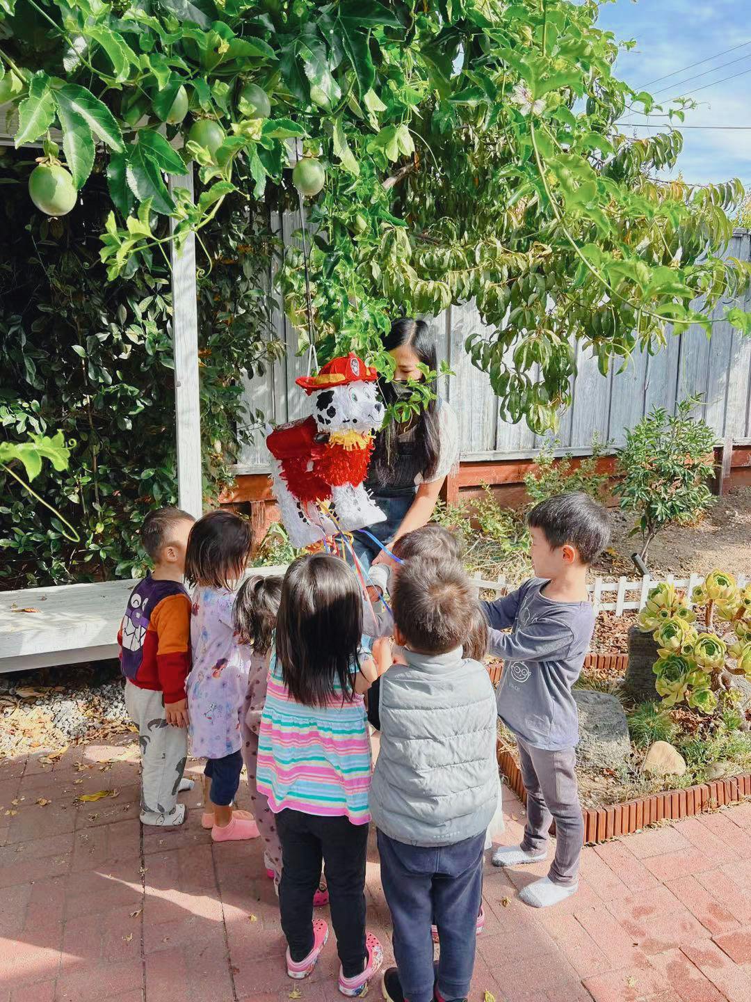 Adult and children gathered around a piñata